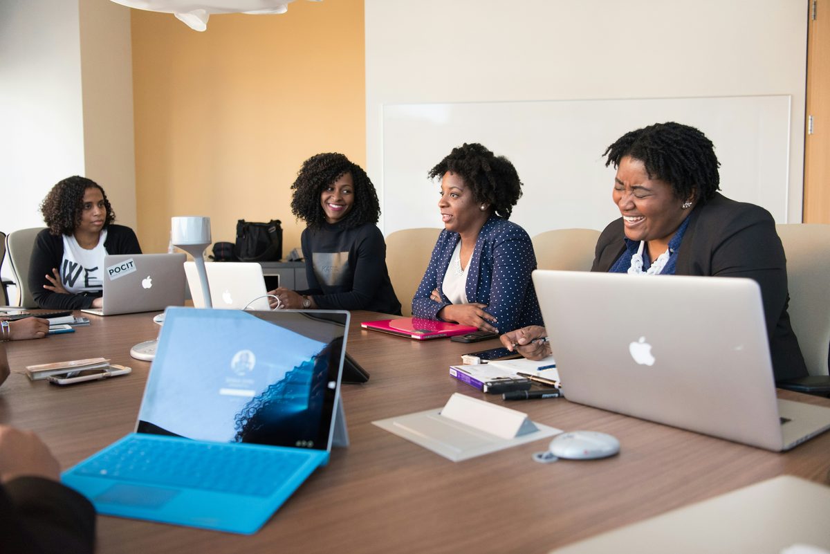 Corporate team meeting around a boardroom table with laptops